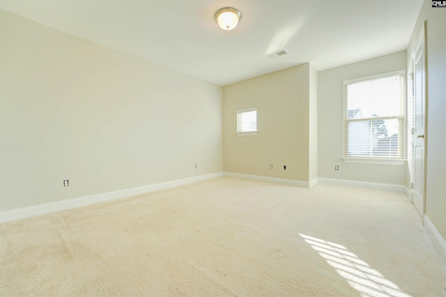 spare room with visible vents, light colored carpet, and baseboards