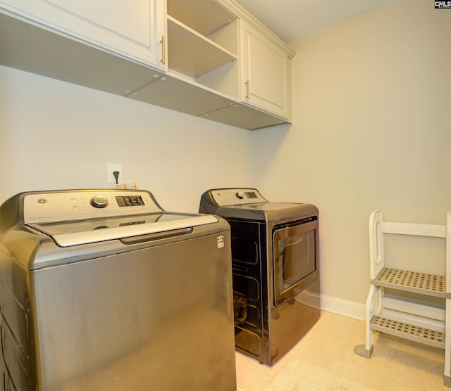 washroom with baseboards, cabinet space, and washing machine and clothes dryer