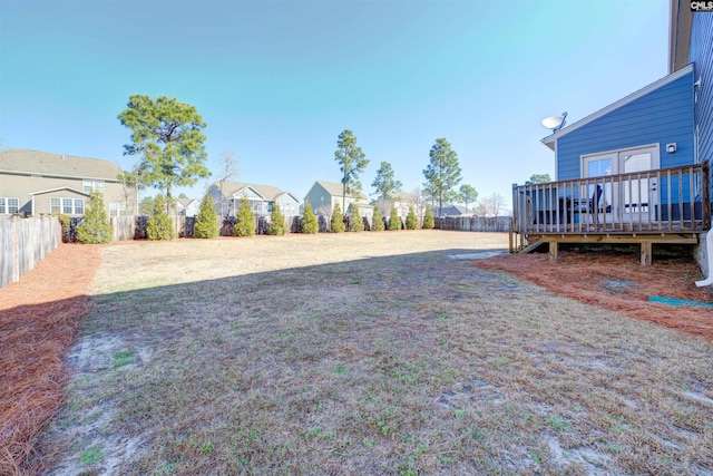 view of yard featuring a fenced backyard, a residential view, and a wooden deck