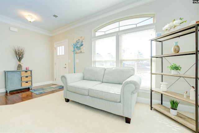 living room with crown molding, wood finished floors, baseboards, and visible vents