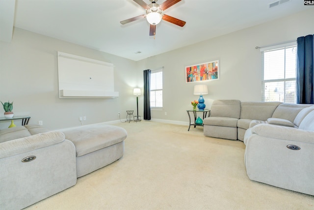 carpeted living room with visible vents, baseboards, and a ceiling fan