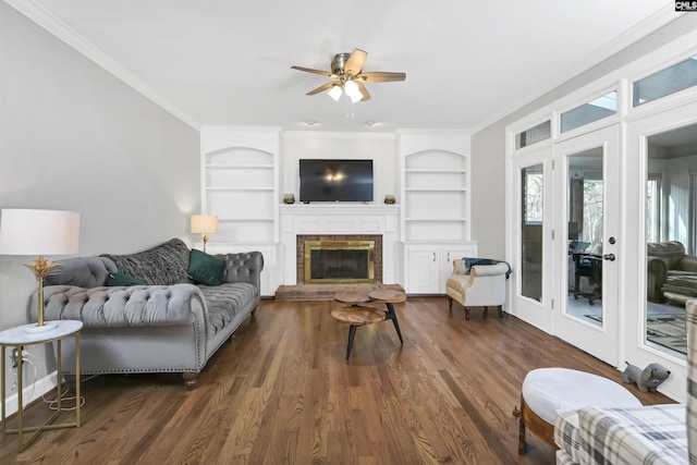 living area featuring built in shelves, wood finished floors, a ceiling fan, and crown molding