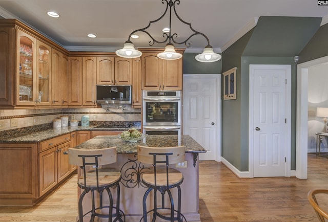 kitchen with tasteful backsplash, glass insert cabinets, light wood-type flooring, a kitchen bar, and appliances with stainless steel finishes