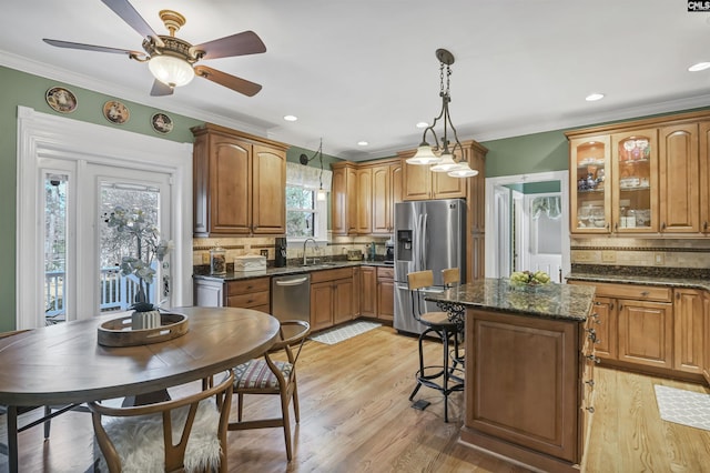 kitchen with glass insert cabinets, crown molding, decorative backsplash, light wood-style floors, and stainless steel appliances