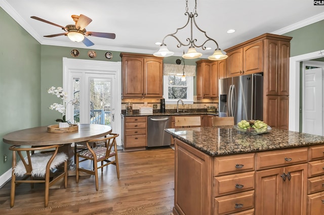 kitchen with appliances with stainless steel finishes, crown molding, and a healthy amount of sunlight