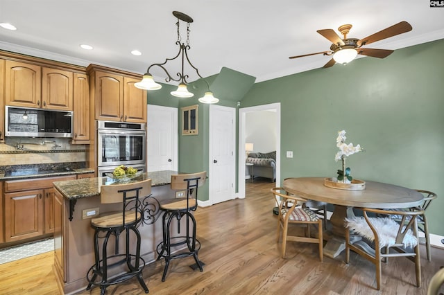 kitchen with stainless steel appliances, a breakfast bar area, a center island, and light wood-style flooring