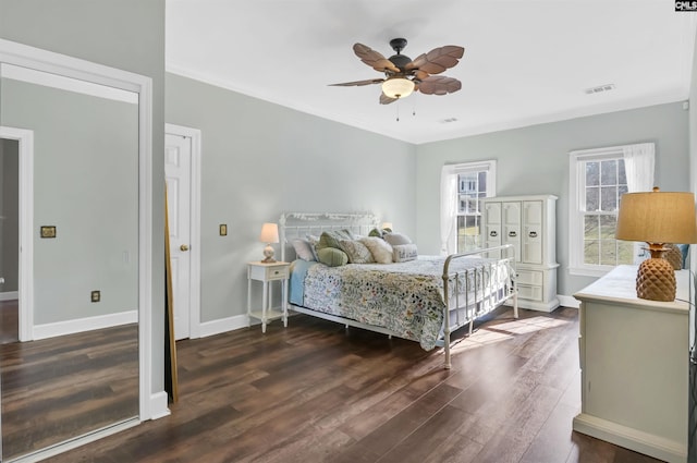 bedroom featuring visible vents, crown molding, baseboards, wood finished floors, and a ceiling fan