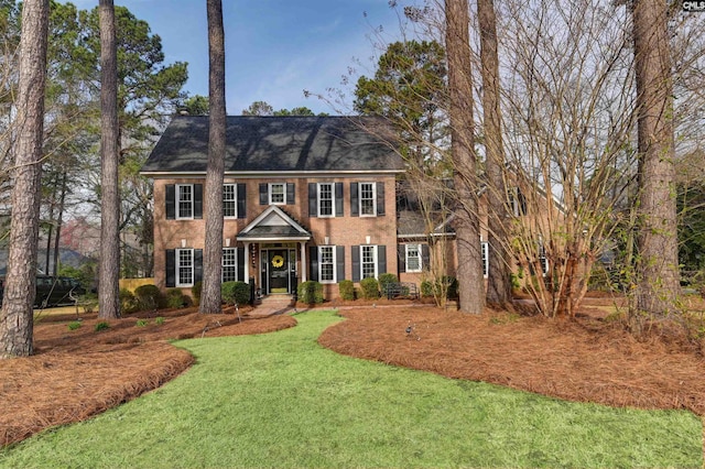 colonial-style house with a front yard and roof with shingles