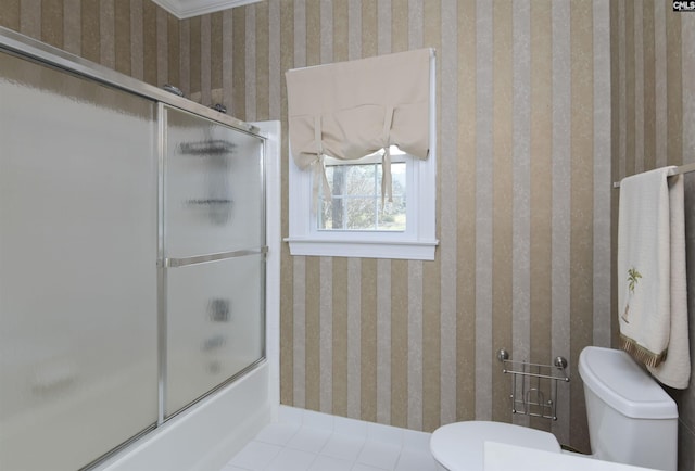 bathroom featuring tile patterned floors, combined bath / shower with glass door, toilet, and wallpapered walls