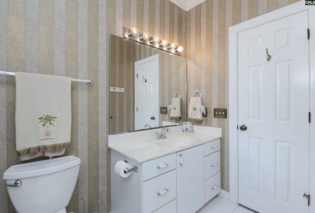 bathroom with toilet, vanity, and wallpapered walls