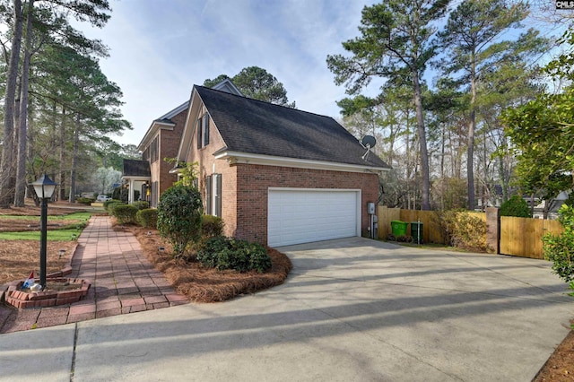 view of side of property with brick siding, a shingled roof, concrete driveway, and fence