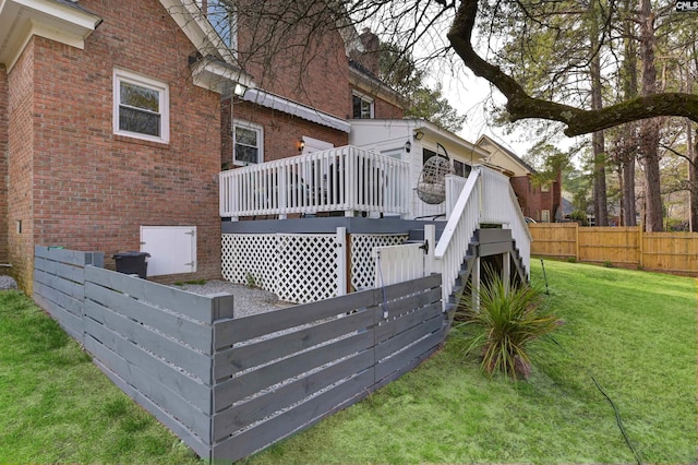 back of property with brick siding, fence, stairway, a deck, and a yard