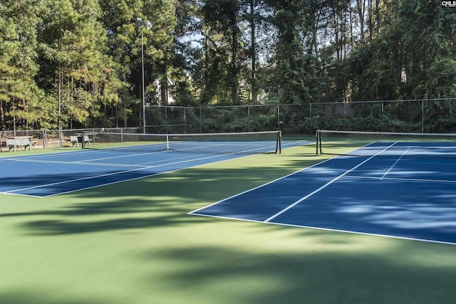 view of tennis court featuring community basketball court and fence