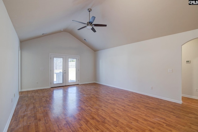 unfurnished room featuring wood finished floors, visible vents, a ceiling fan, arched walkways, and vaulted ceiling