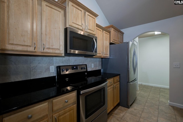 kitchen with baseboards, lofted ceiling, arched walkways, decorative backsplash, and appliances with stainless steel finishes