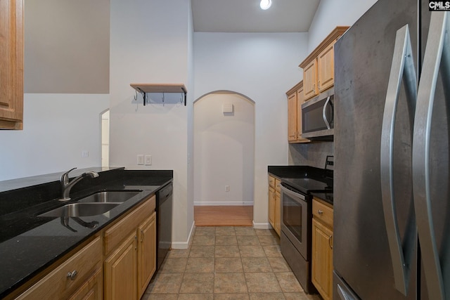 kitchen with a sink, dark stone countertops, tasteful backsplash, stainless steel appliances, and baseboards