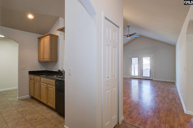 kitchen featuring black dishwasher, vaulted ceiling, arched walkways, a ceiling fan, and a sink