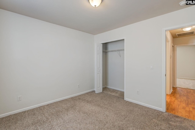 unfurnished bedroom featuring a closet, baseboards, light colored carpet, and visible vents