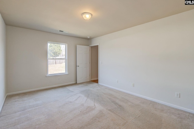 empty room with light colored carpet, baseboards, and visible vents