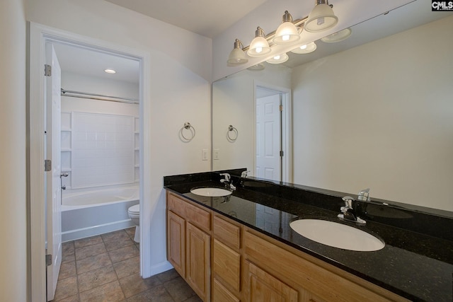 bathroom with double vanity, washtub / shower combination, toilet, and a sink