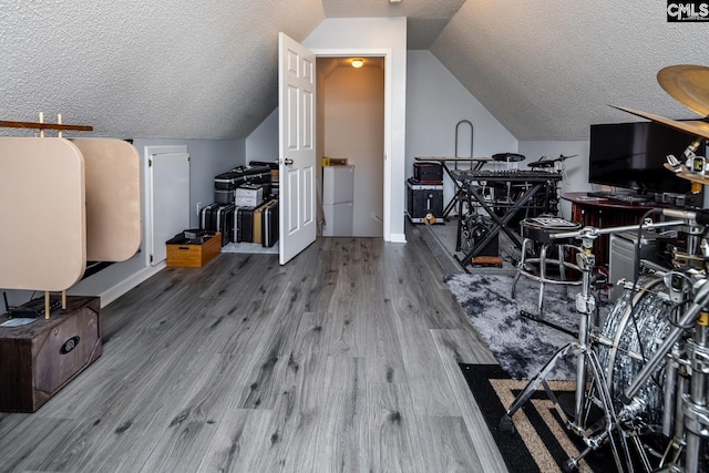 interior space featuring lofted ceiling, a textured ceiling, and wood finished floors