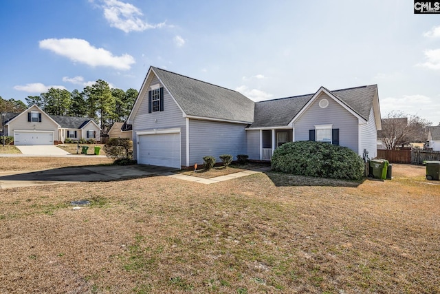 view of front facade with concrete driveway, a garage, fence, and a front lawn