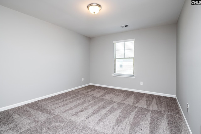 empty room with baseboards, visible vents, and dark colored carpet