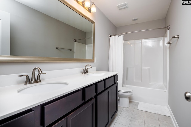 full bath with a sink, toilet, double vanity, and tile patterned flooring