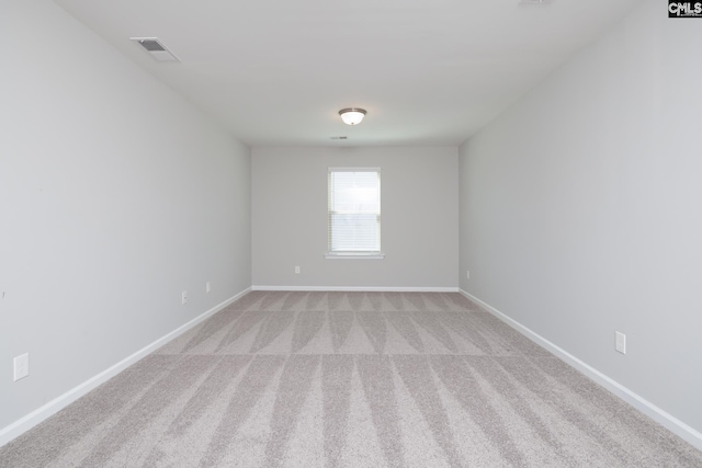 spare room with visible vents, light colored carpet, and baseboards