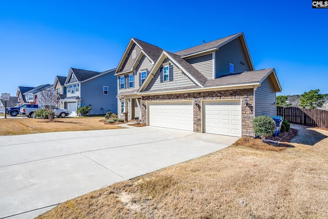 view of front facade with a residential view, stone siding, driveway, and fence