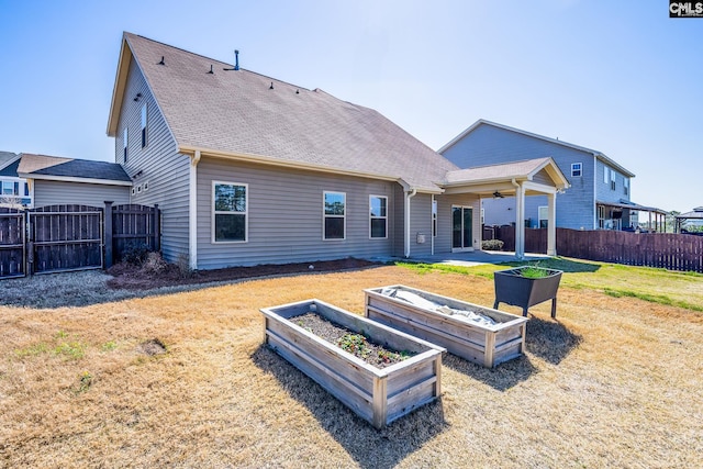 rear view of house with a garden, a lawn, and fence