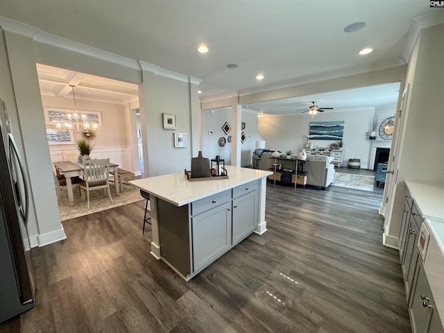 kitchen featuring dark wood-type flooring, open floor plan, ornamental molding, ceiling fan with notable chandelier, and coffered ceiling