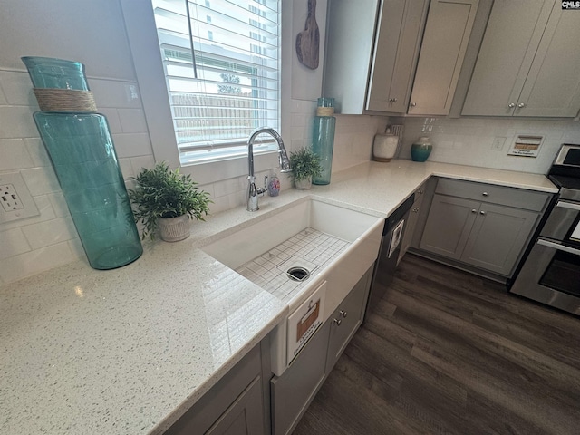 kitchen featuring tasteful backsplash, dark wood finished floors, gray cabinets, range, and a sink