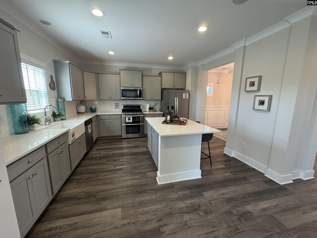 kitchen featuring visible vents, gray cabinets, a sink, appliances with stainless steel finishes, and crown molding