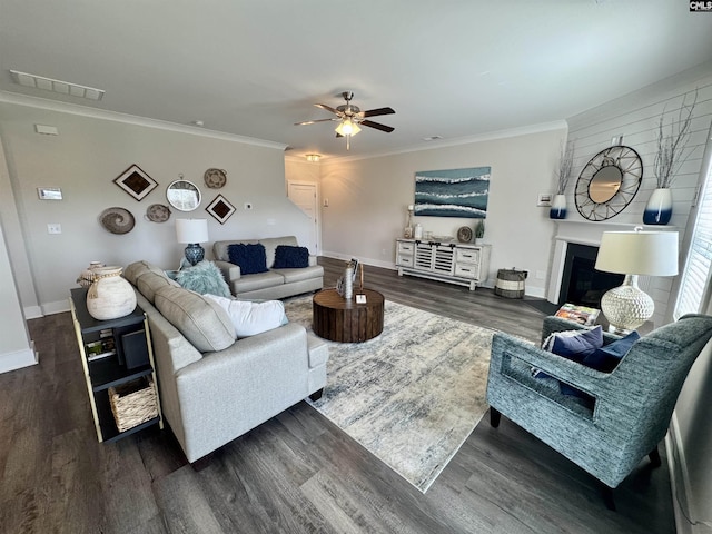 living room with visible vents, dark wood-style flooring, a ceiling fan, and ornamental molding