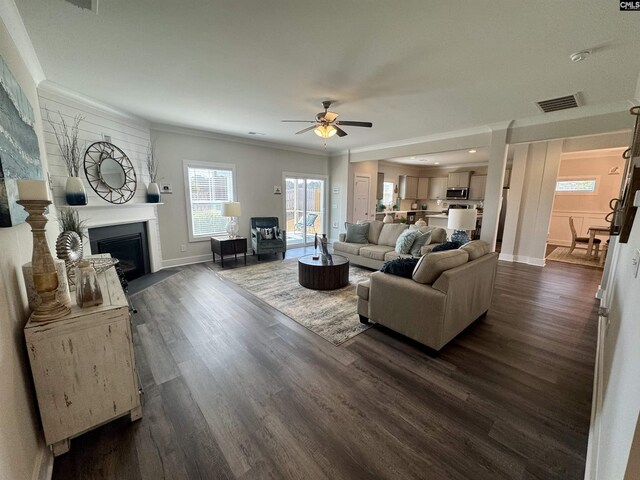 living room with visible vents, a fireplace with flush hearth, ceiling fan, and dark wood finished floors