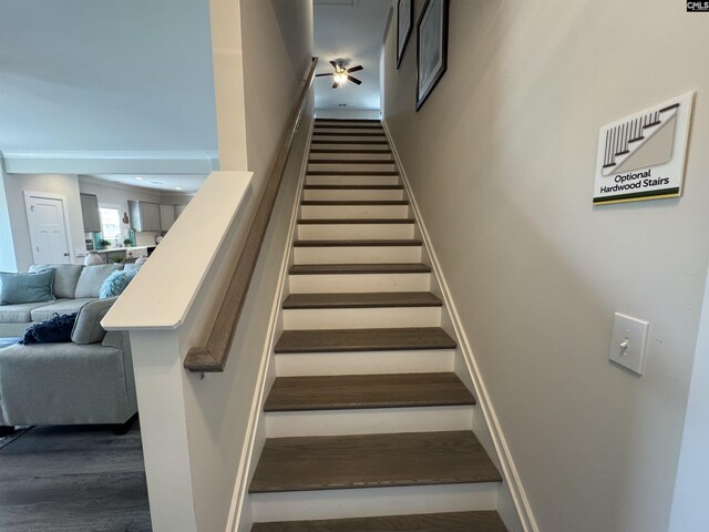 staircase featuring baseboards and ceiling fan