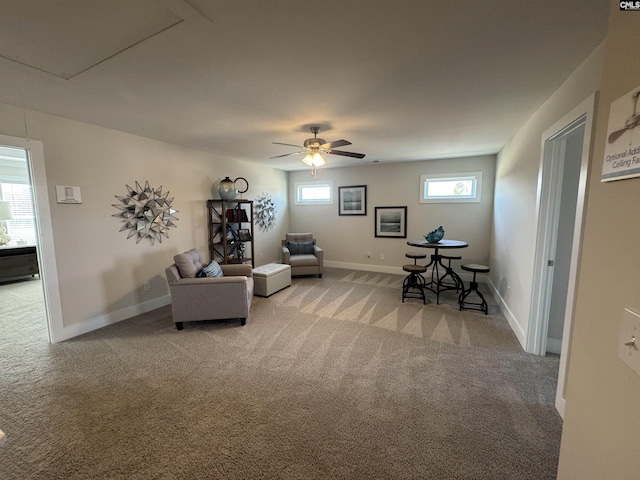 living area featuring baseboards, light carpet, and ceiling fan