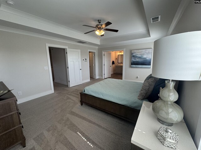 carpeted bedroom with a tray ceiling, baseboards, visible vents, and connected bathroom