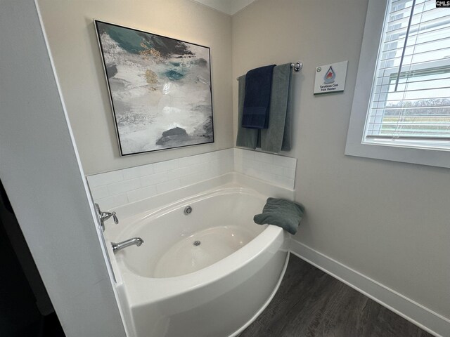 bathroom featuring a bath, wood finished floors, and baseboards