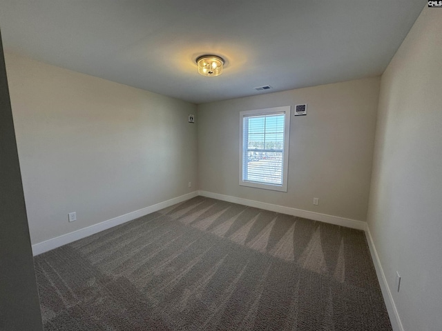 spare room with visible vents, baseboards, and dark colored carpet