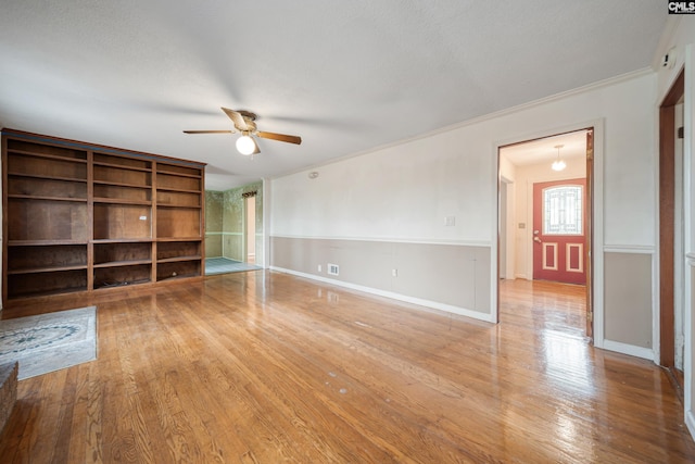 unfurnished living room with baseboards, wood finished floors, ceiling fan, and ornamental molding