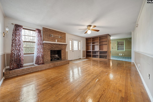 unfurnished living room featuring a wealth of natural light, ceiling fan, and wood-type flooring