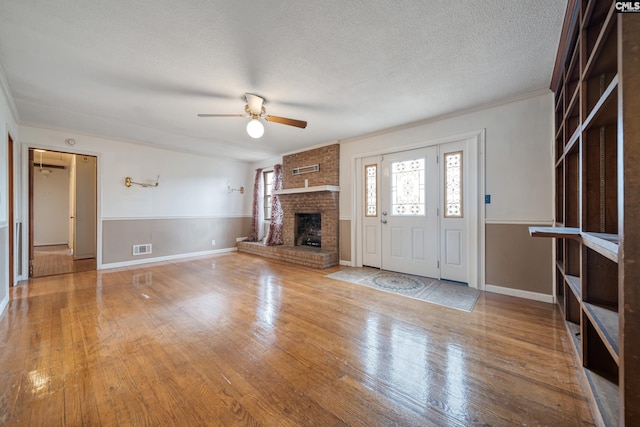 unfurnished living room with visible vents, a textured ceiling, ceiling fan, and hardwood / wood-style floors