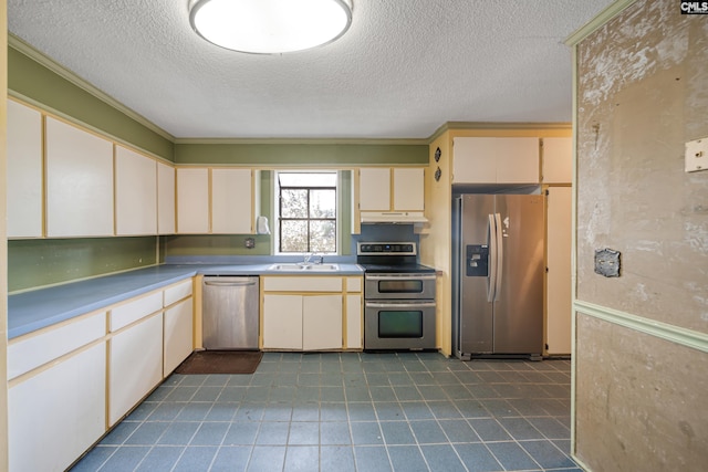 kitchen with a sink, cream cabinetry, under cabinet range hood, and stainless steel appliances