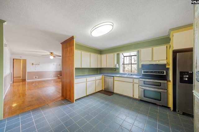 kitchen with visible vents, a sink, cream cabinetry, under cabinet range hood, and appliances with stainless steel finishes