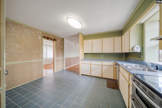 kitchen featuring ornamental molding, appliances with stainless steel finishes, cream cabinetry, a textured ceiling, and a sink