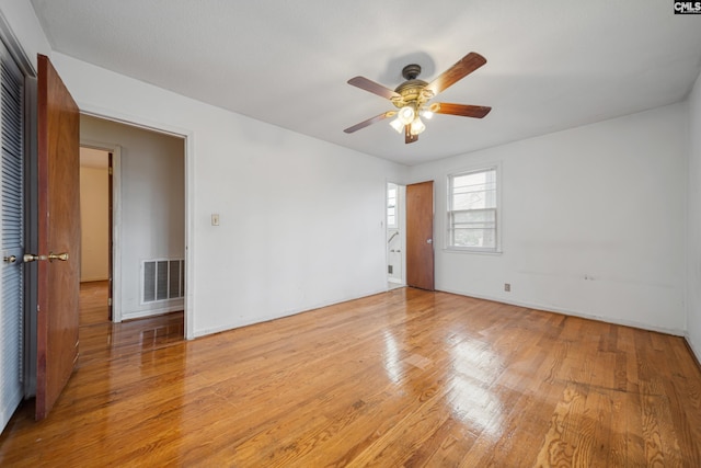 spare room with light wood finished floors, visible vents, and a ceiling fan