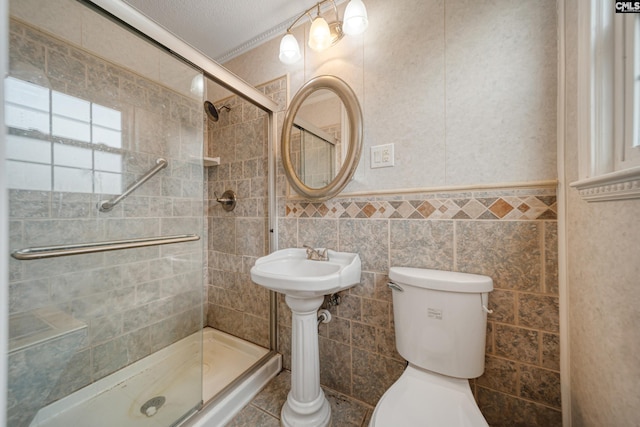 full bath featuring tile walls, toilet, a stall shower, and wainscoting