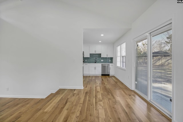 kitchen with baseboards, white cabinetry, light countertops, stainless steel dishwasher, and tasteful backsplash